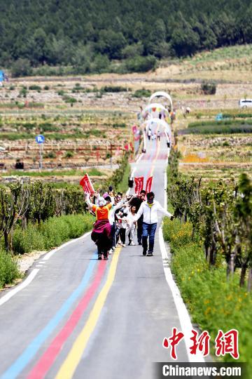 在一家玫瑰加工企业的生态产业园内，一群游客在田间道路上唱跳自如，欢呼雀跃。　沙见龙 摄